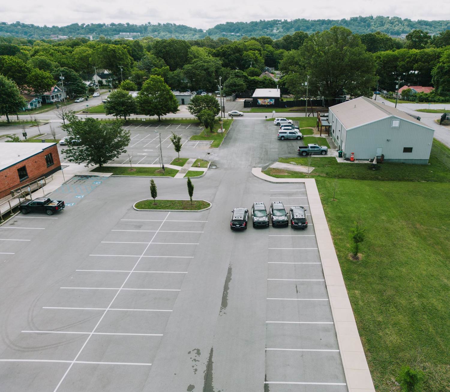 Drone view of a freshly striped commercial parking lot beside a low commercial building